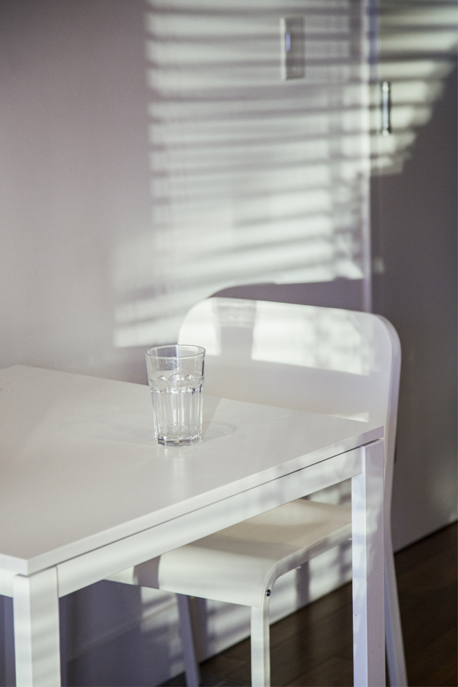﻿Water glass sitting on white kitchen table